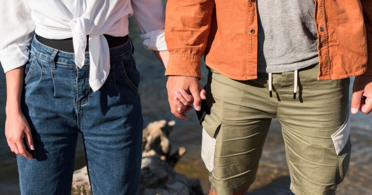 A man and woman hold hands on a rock, showcasing a moment of connection and harmony in nature.