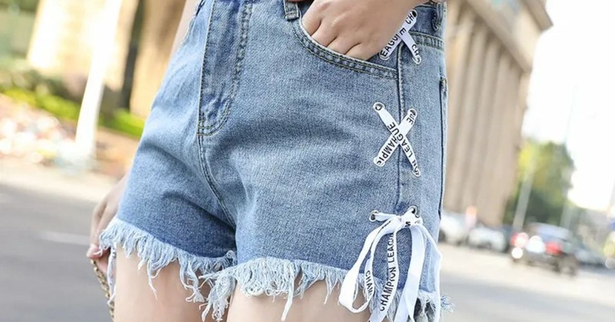  A woman in denim shorts and white sneakers, showcasing a casual summer outfit paired with a green shirt.